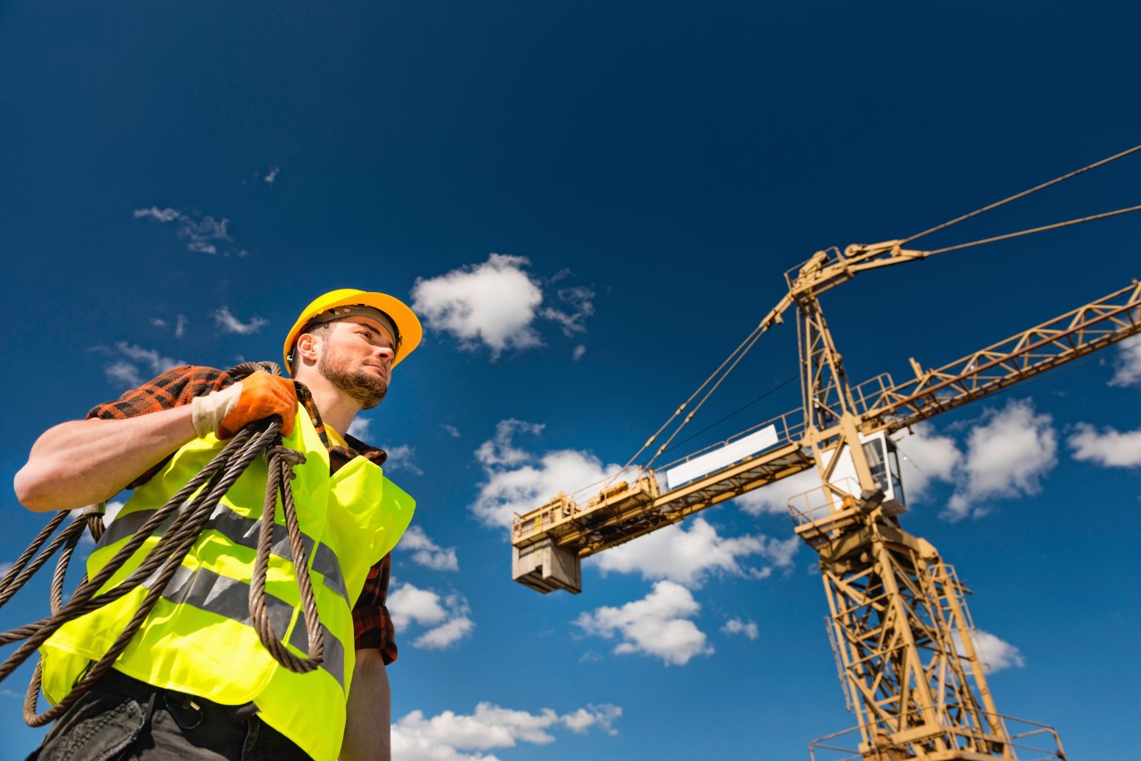 media-1779437953_manual-worker-wearing-hardhat-reflective-clothing-working-construction-site-sunny-dayjpg